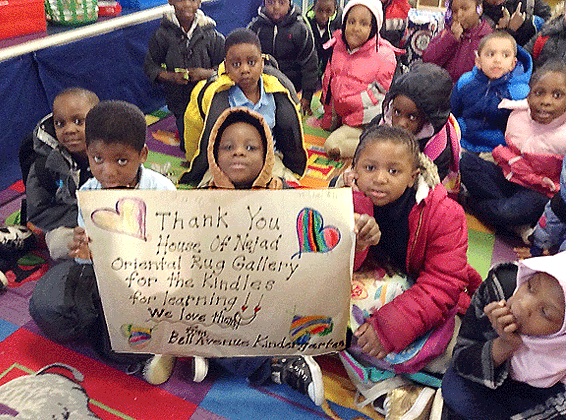 students holding the poster they made thanking Nejad Rugs