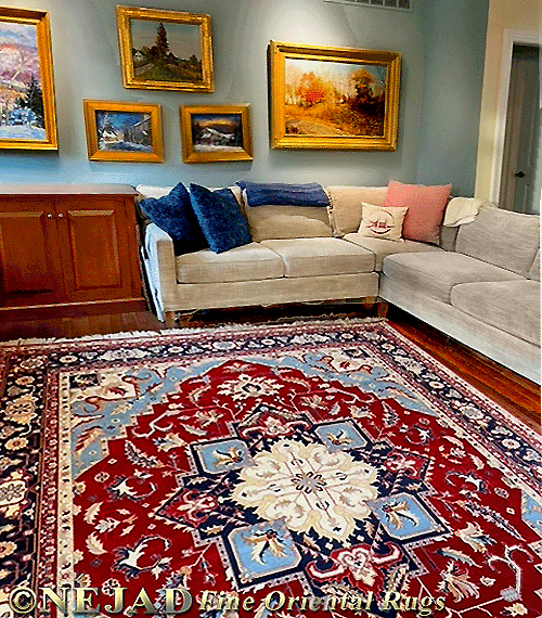 This interior living room setting achieves
a harmonious, color-coordinated effect as 
the colors featured in the several paintings 
on the wall are reflected in the bright and 
colorful Heriz Oriental Persian rug. Even the 
blonde color of the wood frames is picked up 
in the border color of the rug.